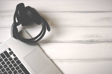 Beyaz ahşap çalışma masasında dizüstü bilgisayar ve eski kulaklıklar