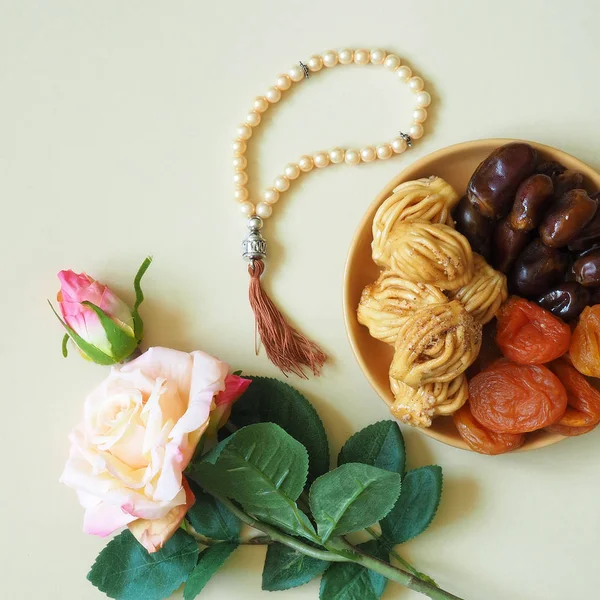 Sweets, dates, dried apricots on a plate on a beige background. Flower. The concept of Ramadan, iftar.