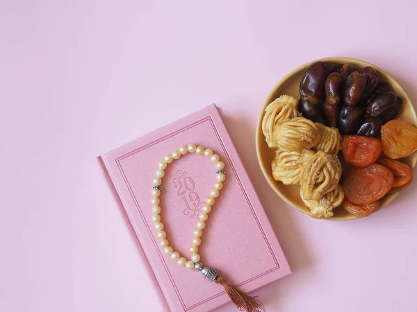 Sweets, dates, dried apricots on a plate on a pinkbackground. The concept of Ramadan, iftar..