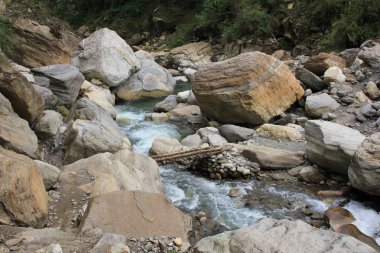 Kimrong Khola, Ghandruk yakınlarındaki nehir, Nepal. Ahşap köprü ve büyük kaya.