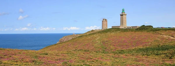 Old lighthouse and flowers at Cap Frehel, Brittany. Popular landmark at the French Coast. English Channel.