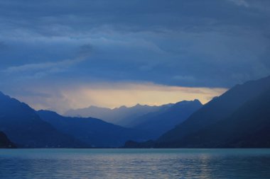 Brienz Gölü'nde yaz sahnesi. Günün son güneş ışığı ve Interlaken üzerinde fırtına, İsviçre.
