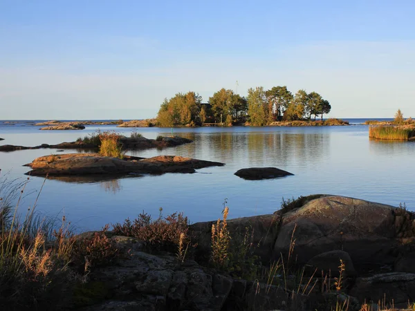 Gün batımından hemen önce üzerinde bir ev olan küçük bir ada. İsveç 'in Vanern Gölü kıyısındaki manzara.