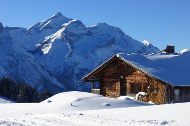 Kar Oldenhorn 'u ve eski bir çiftlik evinin dış cephesini kapladı, Gstaad, İsviçre yakınlarındaki Winte sahnesi.
