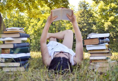 Çimenler üzerine kitap okuyan kadın