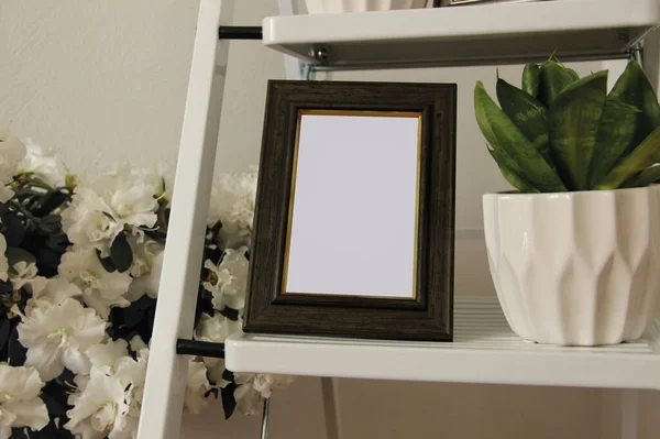 Ev bitkileriyle çevrili boş ahşap fotoğraf çerçevesi. Yatak odasında rahat detaylar.. 