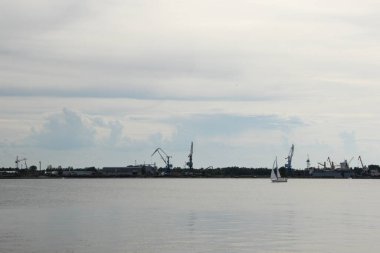 Beyaz yelkenli yat limana giriyor. Deniz kenarında akşam manzarası. 