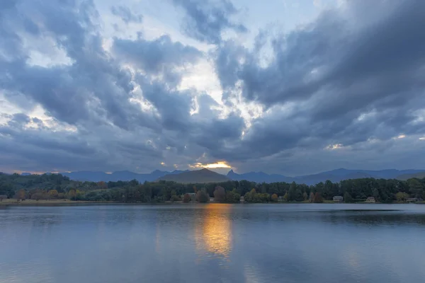 Gelber Sonnenschein durch die Wolken spiegelt sich auf dem Wasser — Stockfoto