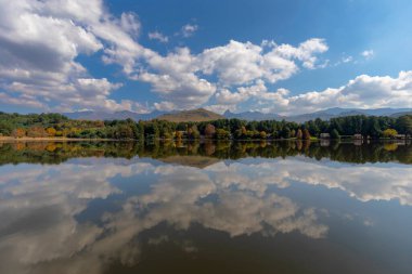 Bulutlar ve sonbahar renkli ağaçlar suyu yansıtır