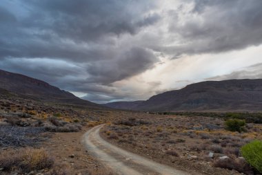 Tankwa Karoo NP 'de kara bulutların altında toprak yol