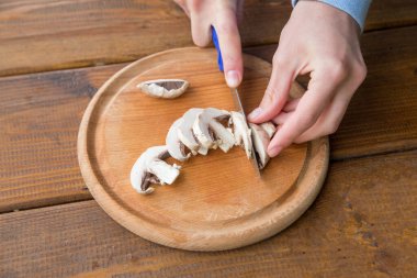 Pişirmek için şampiyon mantarları dilimliyorum.