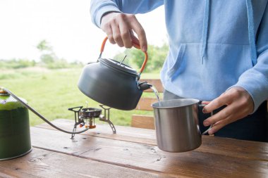 Kız kamp alanında ya da piknikte çay ve kahve yapıyor.