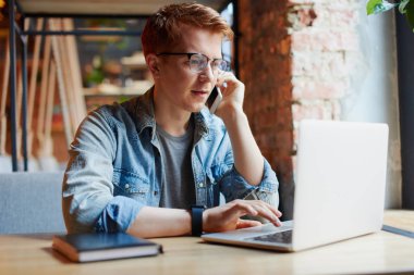 Genç adam kafede dizüstü bilgisayarüzerinde çalışıyor.