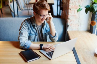 Genç adam kafede dizüstü bilgisayarüzerinde çalışıyor.