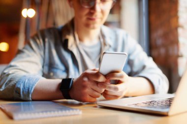 Genç adam kafede dizüstü bilgisayarüzerinde çalışıyor.