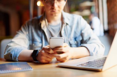 Genç adam kafede dizüstü bilgisayarüzerinde çalışıyor.