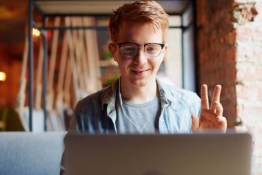 Genç adam kafede dizüstü bilgisayarüzerinde çalışıyor.