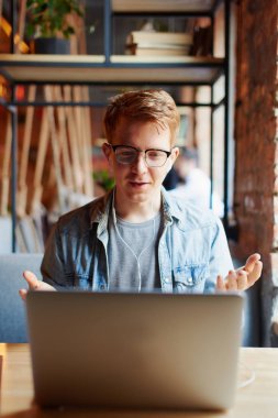 Genç adam kafede dizüstü bilgisayarüzerinde çalışıyor.