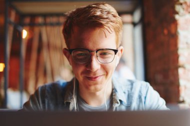 Genç adam kafede dizüstü bilgisayarüzerinde çalışıyor.