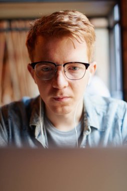 Genç adam kafede dizüstü bilgisayarüzerinde çalışıyor.