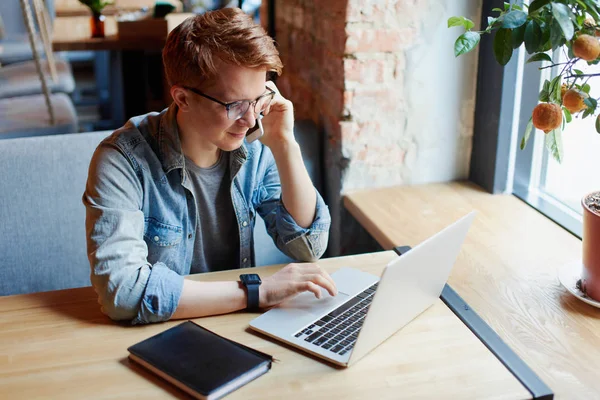 Genç adam kafede dizüstü bilgisayarüzerinde çalışıyor.