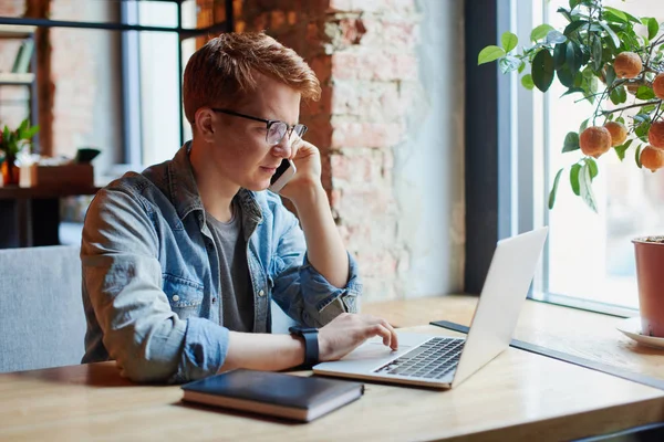 Genç adam kafede dizüstü bilgisayarüzerinde çalışıyor.