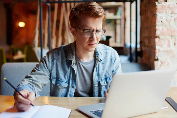 Genç adam kafede dizüstü bilgisayarüzerinde çalışıyor.