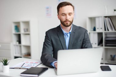 Ofiste ki dizüstü bilgisayar üzerinde çalışan adam.