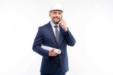 Foreman elinde çizimler ilerler ve telefonda konuşuyorlar.