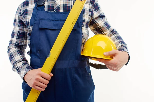 Primer plano. Ingeniero sostiene un casco de construcción y regla de nivelación en sus manos . — Foto de Stock