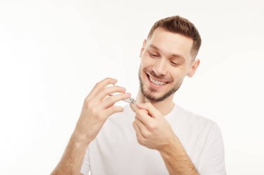 Gülümseyen adam beyaz bir arka plan üzerinde tırnak keser