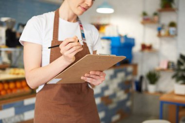 Barista not defterine yazarken ayakta.