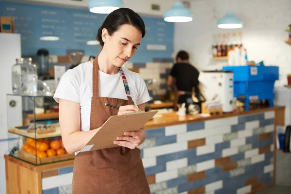 Barista not defterine yazarken ayakta.