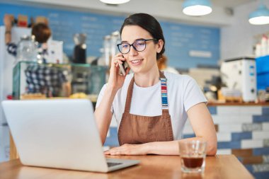 Barista gözlük takıyor ve dizüstü bilgisayar üzerinde çalışıyor.