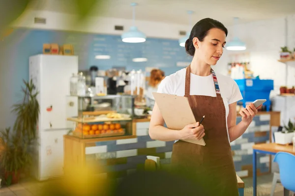 Barista de pé enquanto escrevia no bloco de notas . — Fotografia de Stock