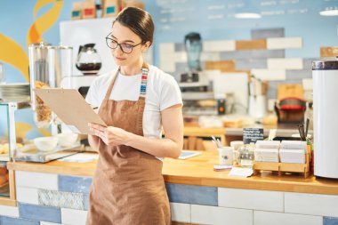Barista not defterindeki bilgileri kontrol ediyor.