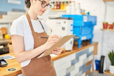 Barista not defterindeki bilgileri kontrol ediyor.