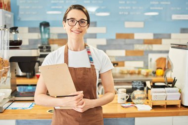 Barista not defterindeki bilgileri kontrol ediyor.