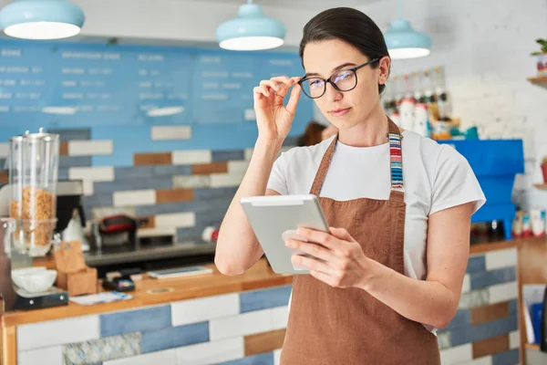 Tablet ile çalışan kahverengi önlük Barista.