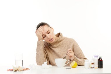 Ağrıyan kafası olan hasta kadın tıbbi malzemelerle çevrili masada oturuyor.