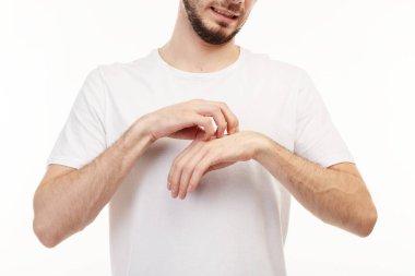 Kaşıntı yüzünden kendini tırmalayan beyaz tişörtlü bir adamın yakınlığı.