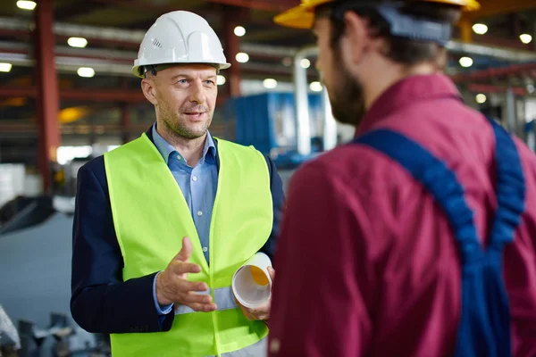 Foreman fabrikada mühendise talimatlar verir.