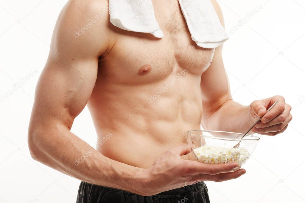 Close up. The athlete eats cottage cheese on a white background