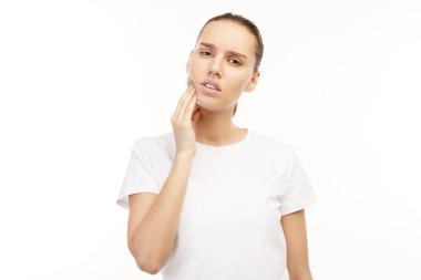 Ağrıyan dişleri olan beyaz tişörtlü kadın.