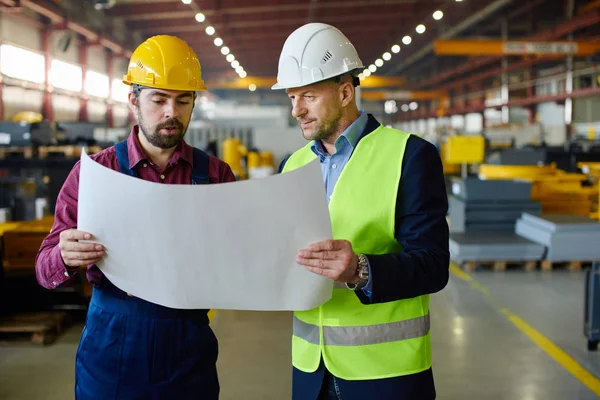 Ingenieros en sombreros duros trabajando en un proyecto en la planta industrial . — Foto de Stock