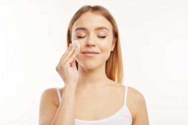 Sarışın kız bir pamuk ped ile onu makyaj silerek.