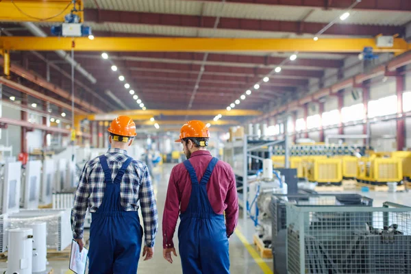 Ingenieros caminando por la planta en la que trabajan disparados por la espalda . — Foto de Stock