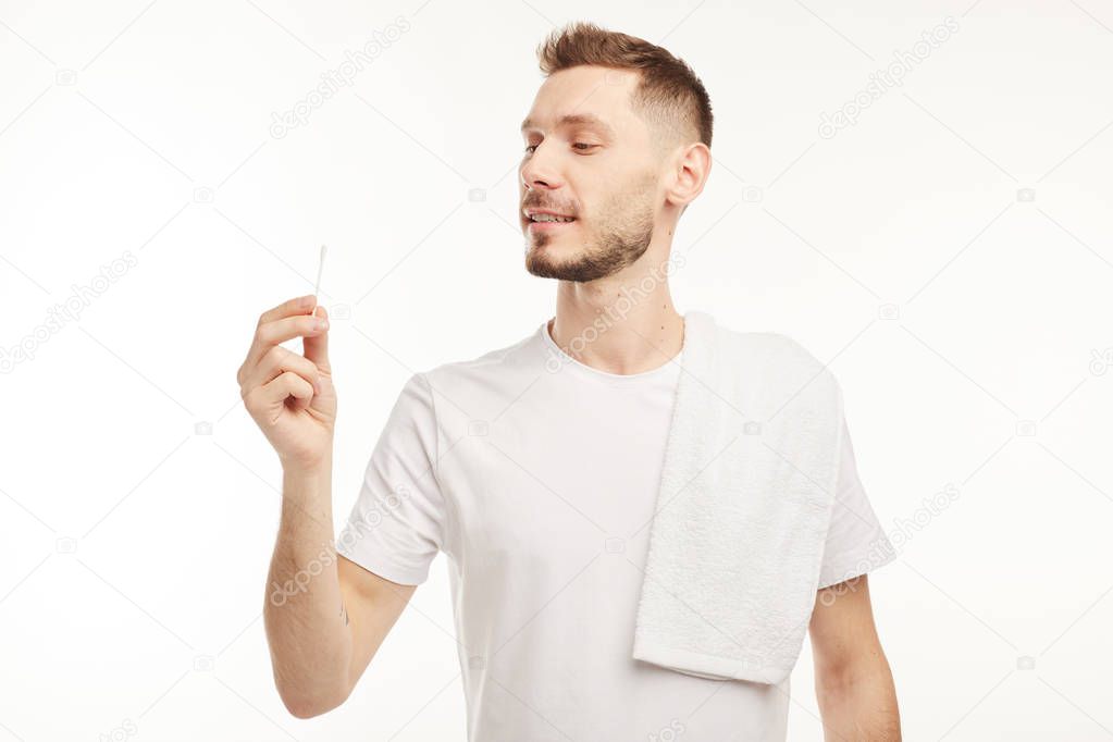 Man holding cotton swab and looking at it.