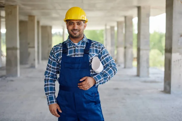 Ingeniero sonriente en casco de construcción amarillo mira a la cámara . — Foto de Stock