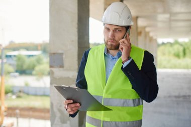 Telefonda bir kask görüşmeler bir mühendis ve siyah bir not defteri tutar.